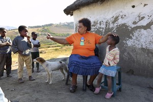 Pic of woman in front of hut with two children