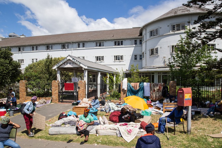 Photo of building with people\'s beds on the lawn