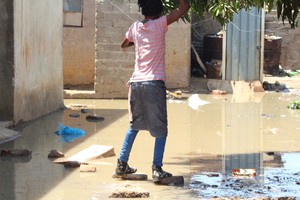 Photo of woman crossing puddle of sewage