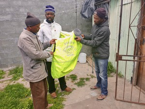 Photo of three men holding up a reflector jacket