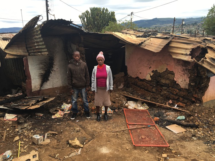 Photo of two people in front of burned house