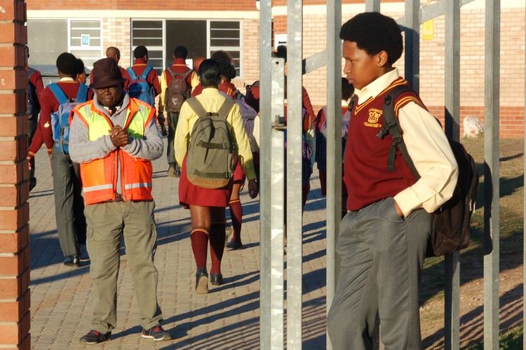 Photo of learner with Afro outside his school\'s gate.