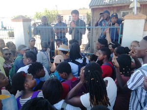 Photo of man behind fence talking to students